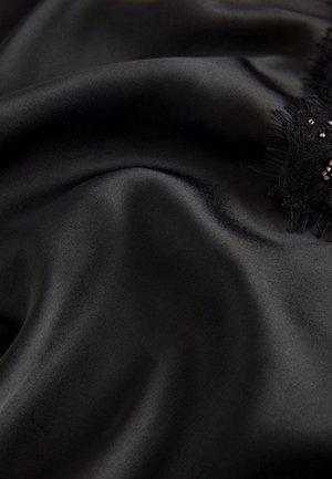 Schwarzer Satinstoff mit glatter, glänzender Textur. Entlang einer Kante verziert mit filigraner schwarzer Spitze und dezenten goldenen Verzierungen.