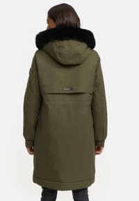 Olive green parka with a black faux fur-lined hood. Features elastic cuffs and a drawstring waist, designed for enhanced warmth and comfort.