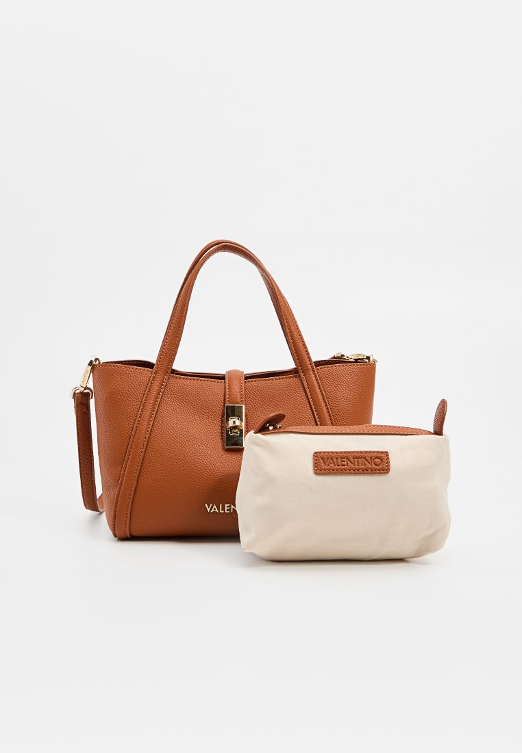 Bruine handtas van gepolijst leer met een gouden sluiting, korte handvatten en een verwijderbare crèmekleurige pouch met een bruine label. Compact en functioneel ontwerp.