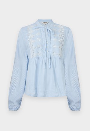 Blouse bleu clair à manches longues avec rayures blanches verticales, patte de boutonnage à l'avant, col noué et broderie florale blanche sur la poitrine.