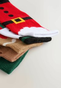 Kolorowe skarpetki w świątecznym klimacie, w czerwonym kolorze z czarnymi i żółtymi akcentami, brązowe, zielone i czarne, ułożone w stos o różnych fakturach i wzorach.