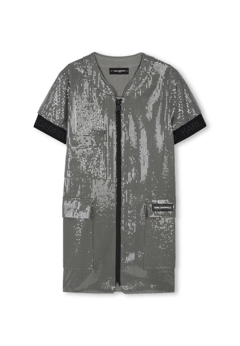 Robe en sequins argentés avec des manches courtes, fermeture éclair et deux poches sur le devant. Présente une texture côtelée et une bande logo noire au niveau des manches.