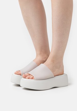 Sandali platform bianchi con una finitura opaca, dotati di una ampia fascia traslucida e design aperto sulla punta, che mette in mostra la texture naturale della pelle.