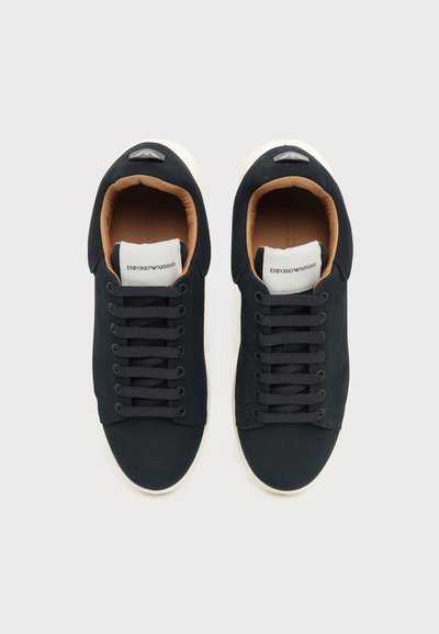 Paire de baskets basses noires avec semelles blanches et logo Emporio Armani sur la languette et la languette du talon, vues de dessus.