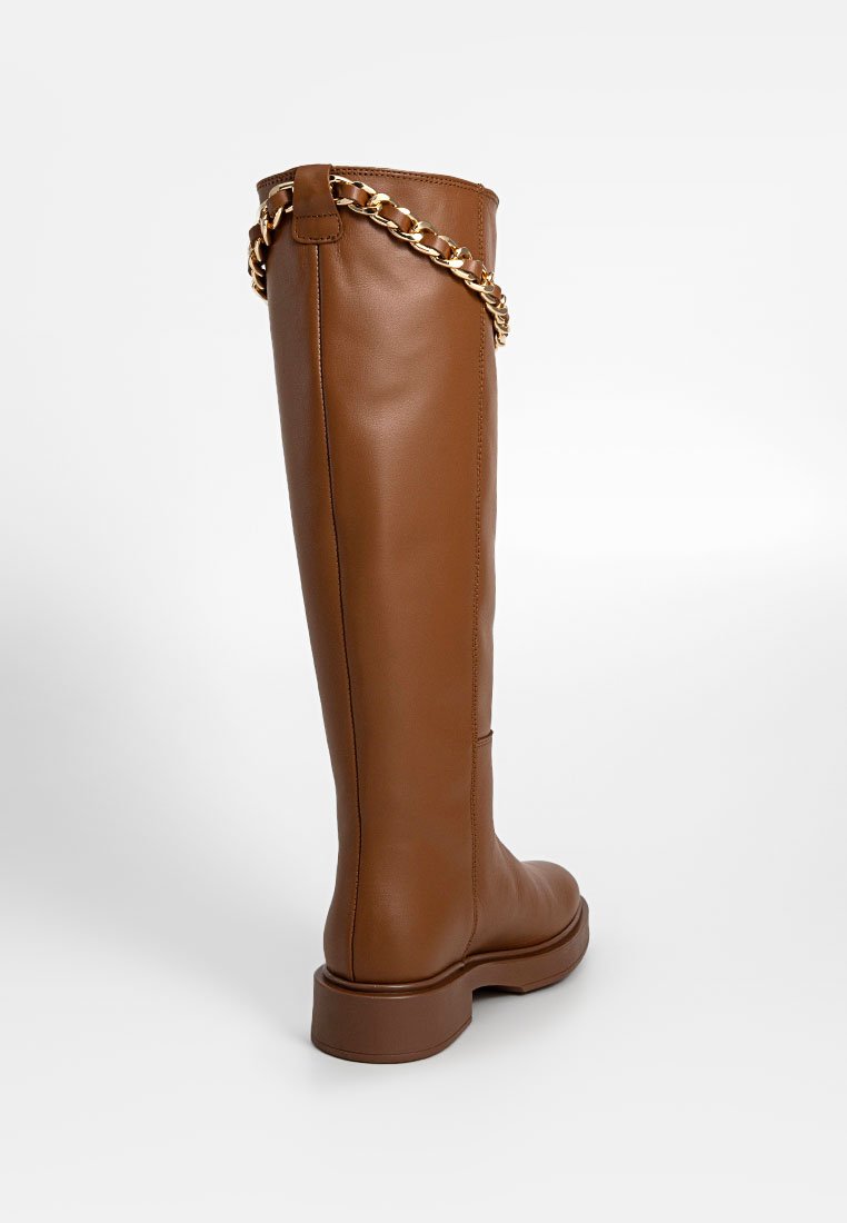 Hoge bruine faux leren laars met een dikke zool en een kettingaccent bovenaan. Soepele textuur met minimale stikseldetails.