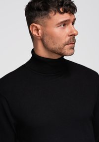 Czarny sweter z golfem, wykonany z gładkiego, lekkiego materiału, charakteryzujący się dopasowanym krojem i prążkowym kołnierzem, podkreślający prosty i klasyczny wygląd.