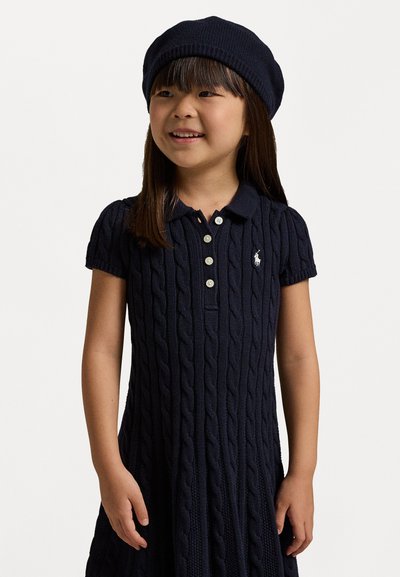 Vestido de punto en azul marino con cuello de solapa y mangas cortas, que cuenta con tres botones y un pequeño emblema en el pecho.