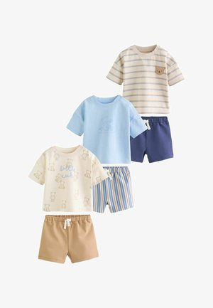 Három garnitúra kisgyermek ruházat rövid ujjú felsőkkel és rövidnadrágokkal; a minták között macik, csíkok és egyszínűek szerepelnek bézs, kék és krém színekben.