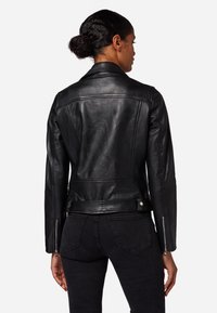 Schwarze Lederjacke mit taillierter Passform, Reißverschlussmanschetten und Kragen. Glatte Textur, minimale Nähte und Akzente auf dem Rückenteil.