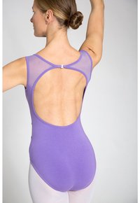 Lila Trikot mit durchsichtigen Mesh-Einsätzen, offenes Rückendesign und verstellbare Hardware-Details. Getragen mit hautfarbenen Strumpfhosen, die eine glatte Textur zeigen.