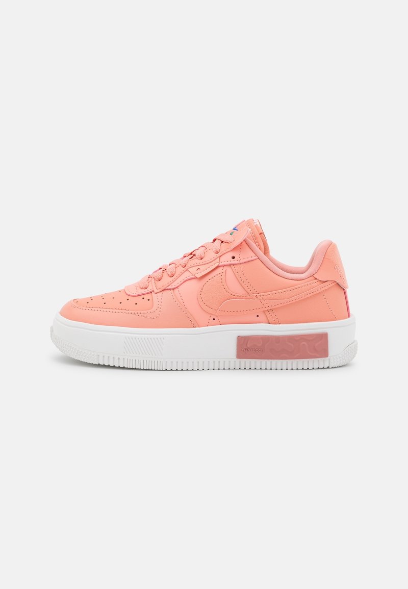 Pink synthetic leather sneaker with a white rubber sole, textured accents, and a transparent pink section on the heel. Traditional lace closure.