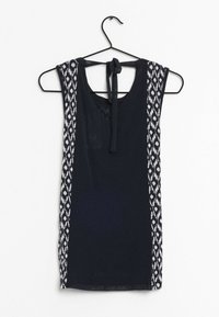 Débardeur bleu marine avec des accents blancs à motifs sur les côtés, doté d'un dos avec ouverture en forme de goutte et d'un lien au niveau de l'encolure. Tissu léger.