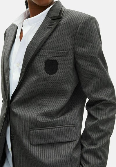 Grijs gestreepte blazer met een zwarte revers, voorzien van een borszak met een embleem en een enkele zak aan de voorkant.