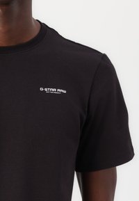 Zwarte G-Star Raw t-shirt met een klassieke ronde hals, zachte katoenmaterialen, korte mouwen en een klein wit logo op de linkerkant van de borst.