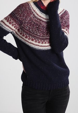 Pull bleu marine avec un motif texturé sur le empiècement bordeaux et crème, comprenant un col rond et des poignets et ourlet côtelés.
