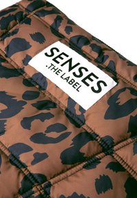Gepolsterte Jacke in Braun und Schwarz mit Leopardenmuster, mit einem sichtbaren weißen Etikett mit dem Text "SENSES .THE LABEL". Steppoptik.