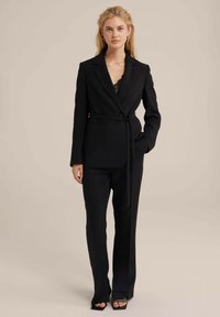 Črn sodni kostim s prilegao jakno, pasom in dolgimi hlačami. Ima satenast ovratnik in eleganten, ravno krojen design.