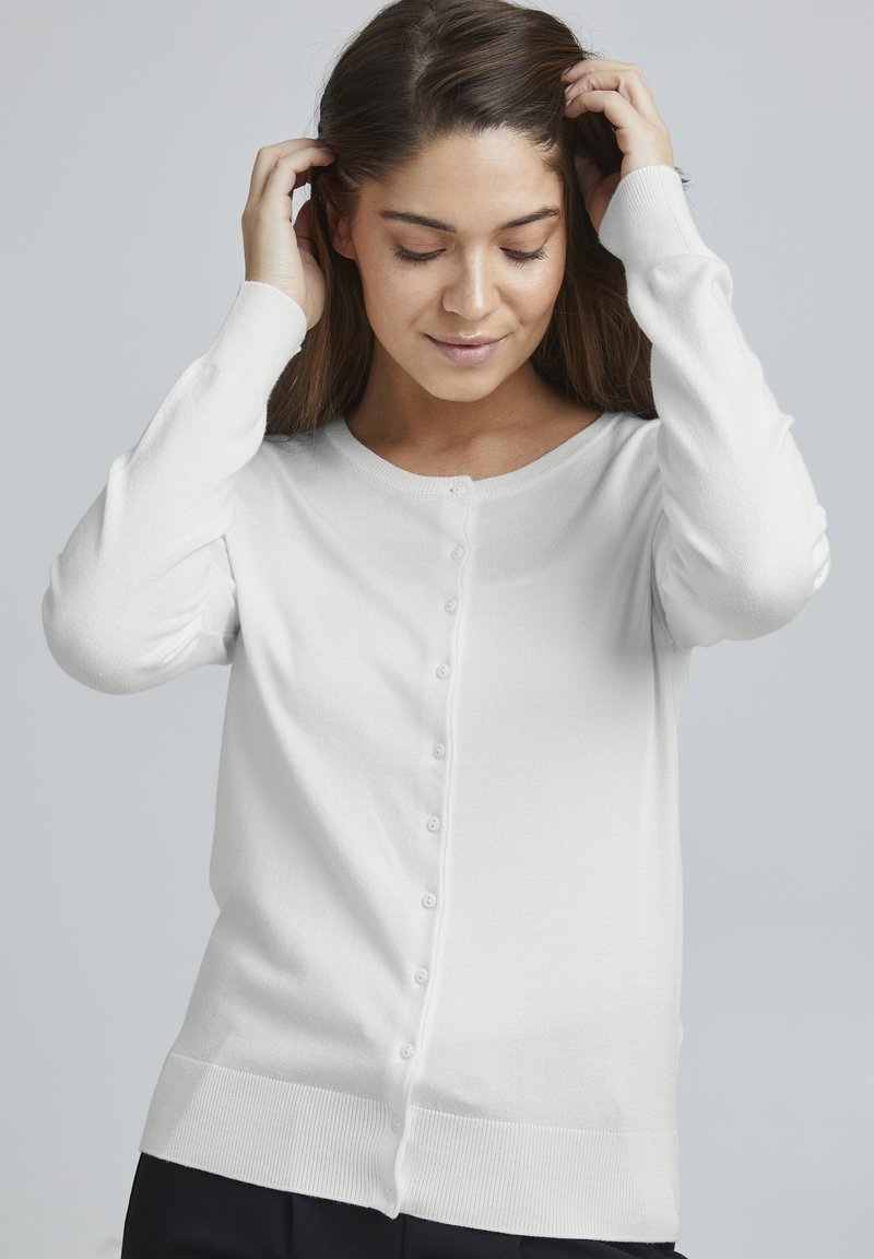 Cardigan bianco a maniche lunghe realizzato in morbido tessuto a maglia, con scollo rotondo, chiusura frontale con bottoni e dettaglio a coste sull'orlo.