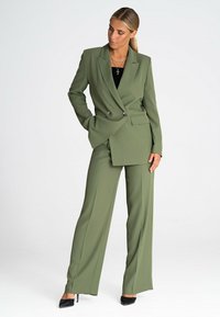 Oliwkowy garnitur ze spersonalizowanym podwójnym żakietem i spodniami o szerokich nogawkach. Tekstura jest gładka, z srebrnymi guzikami i dopasowanymi kieszeniami.