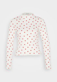 Weißes Langarmoberteil mit einem rüschierten Ausschnitt, das ein sich wiederholendes rotes Herzmuster aufweist. Aus Baumwolle, mit taillierter Passform und gewelltem Saum.