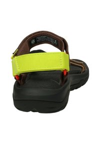 Sandal marrón con suela negra, que presenta una hebilla ajustable de color amarillo brillante y acentos naranjas. Plantilla texturizada para mayor comodidad.