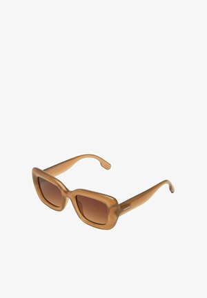 Lunettes de soleil en acétate marron avec une large monture rectangulaire et des verres dégradés. Dotées d'une texture lisse et de branches élégantes, étiquetées "KOMONO".