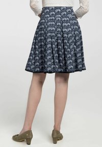 Floraal-patroon geplooide rok van donkerblauwe stof, met een aansluitende taille en een uitlopende zoom. Gemaakt in combinatie met beige, lage hakken.