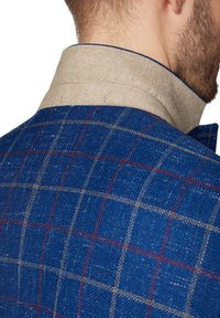 Wełniana marynarka w niebieską kratę, z beżowym filcowym kołnierzem. Teksturowana tkanina z widocznym ściegiem oraz akcentami w kolorze czerwonym i beżowym.