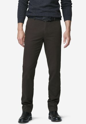 Mann trägt dunkelbraune Slim-Fit-Hosen, schwarzen geflochtenen Gürtel, schwarze Lederschuhe und dunkelgrauen Langarmpullover und steht vor weißem Hintergrund.