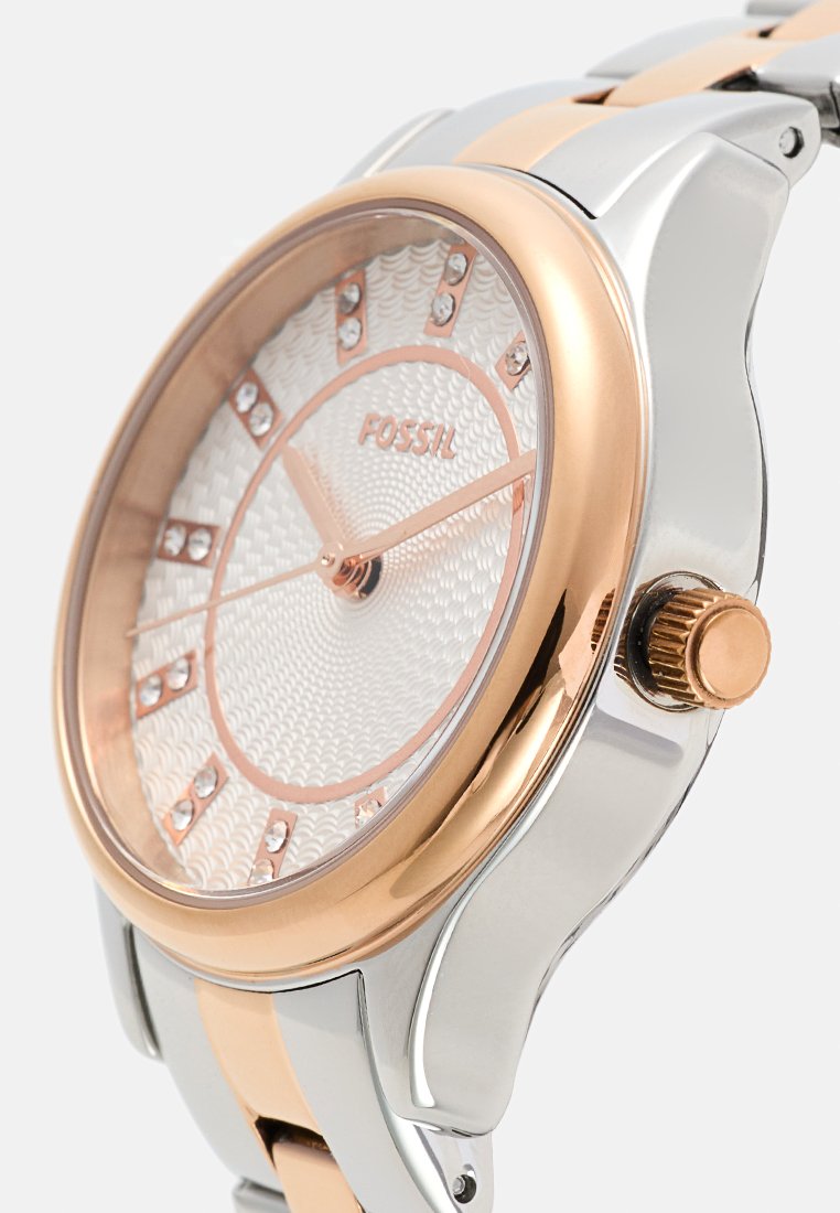 Montre-bracelet en argent et or rose avec un cadran blanc texturé, des index en cristal et une couronne. Présente un bracelet en métal bicolore.