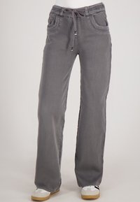 Grijze rechte broek met een koord in de taille, zij- en voorkruiszakken, gedragen met witte en beige sneakers op een effen achtergrond.