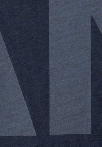 Dunkelblauer Stoff mit unterschiedlichen Farbtönen und geometrischen Formen, darunter Dreiecke und Rechtecke, in einem weichen, strukturierten Strick.