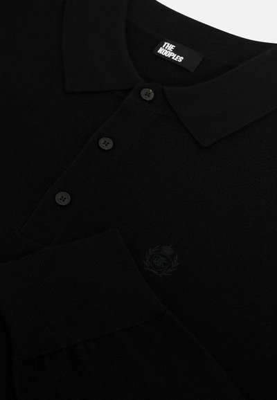 Polo shirt nera in maglia con colletto, pattina con cinque bottoni e un logo ricamato discreto sul petto. Texture morbida e design aderente.