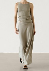 Khaki geribde tanktop en lange maxirok, gemaakt van zachte, gestructureerde stof. De outfit heeft een relaxte pasvorm en een vloeiende drape.