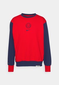Sweat-shirt rouge et bleu marine avec un logo rond au centre, col et poignets côtelés, étiquette près de l'ourlet. Confectionné en tissu doux.