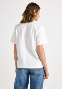 Hvid bomulds T-shirt med korte ærmer, afslappet pasform og lige kant. Stoffet har en glat tekstur og ingen synlige mønstre.