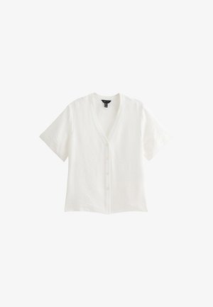 Camicia bianca a maniche corte con scollo a V, con bottoni e tessuto testurizzato. Progettata con una vestibilità morbida e una finitura liscia.