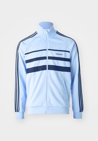 Ljust blå zip-up träningsjacka med marinblå ränder, ribbade ärmslut och ett Adidas-logotyp. Tillverkad av ett mjukt, lätt material.