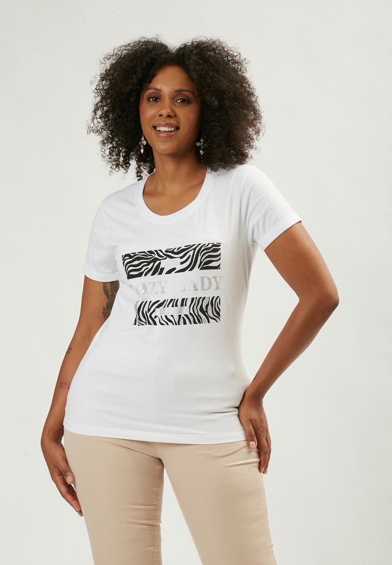 Camiseta blanca con un gráfico de estampado de cebra y el texto "Cozy Lady", de mangas cortas y cuello redondo. Tejido suave, diseño ajustado.
