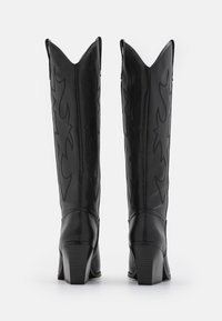Zwarte leren cowboylaarzen met spitse toppen, gedetailleerde stiksels en een verhoogde hak. Het ontwerp bevat gebogen patronen aan de zijkanten.