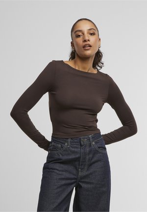 Brun langærmet top lavet af strækbart materiale, med bådudskæring og en tætsiddende design, parret med mørk denim højtaljede jeans.