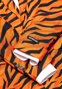 Giacca da abito a strisce arancioni e nere con polsini di camicia bianchi e etichetta "SUITMEISTER", dotata di bottoni neri e motivi incisivi.