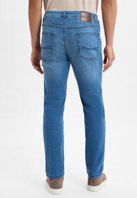 Jeans in denim blu con taglio dritto, caratterizzati da un'etichetta in pelle sulla vita, due tasche posteriori e una finitura leggermente sbiadita.