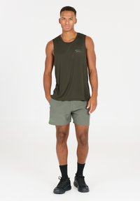 Donkergroene mouwloze sportshirt van textuurstof, gecombineerd met lichtgroene shorts met een logo en accenten. Lichtgewicht ontwerp.