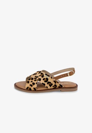 Sandali bassi con stampa leopardata, caratterizzati da una morbida tomaia in pelliccia animale, cinturini incrociati e una cavigliera con fibbia, su una suola marrone liscia.