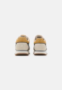 Sport shoes with a beige and gray upper, a tan heel tab, and a textured design. Features a white midsole and gum rubber outsole.