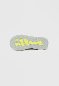 Εξωτερική σόλα αθλητικού παπουτσιού σε ανοιχτό γκρι με υφή στην επιφάνεια και έντονες κίτρινες λαστιχένιες λεπτομέρειες, με κυματιστό μοτίβο για καλύτερη πρόσφυση.