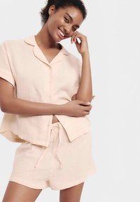 Lichtroze button-down top met korte mouwen en bijpassende shorts, gemaakt van gestructureerde stof met een relaxed fit en een taille met aantrekkoord.