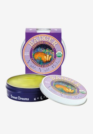 Badger Night-Night Balm i en rund sølvboks. Lokket har lilla emballasje med en illustrajon av en grevling, og inneholder en gul balsam.
