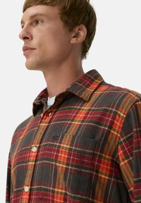Rood, oranje en grijs geruit flanellen shirt met een knop-down kraag, borstzak en zichtbare knoopsluitingen. Zachte stoftextuur.